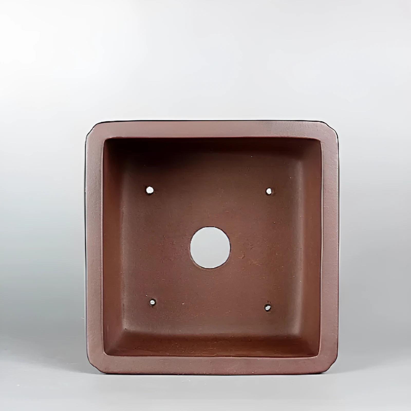 Handmade brown antique style purple clay flower pot on a windowsill.