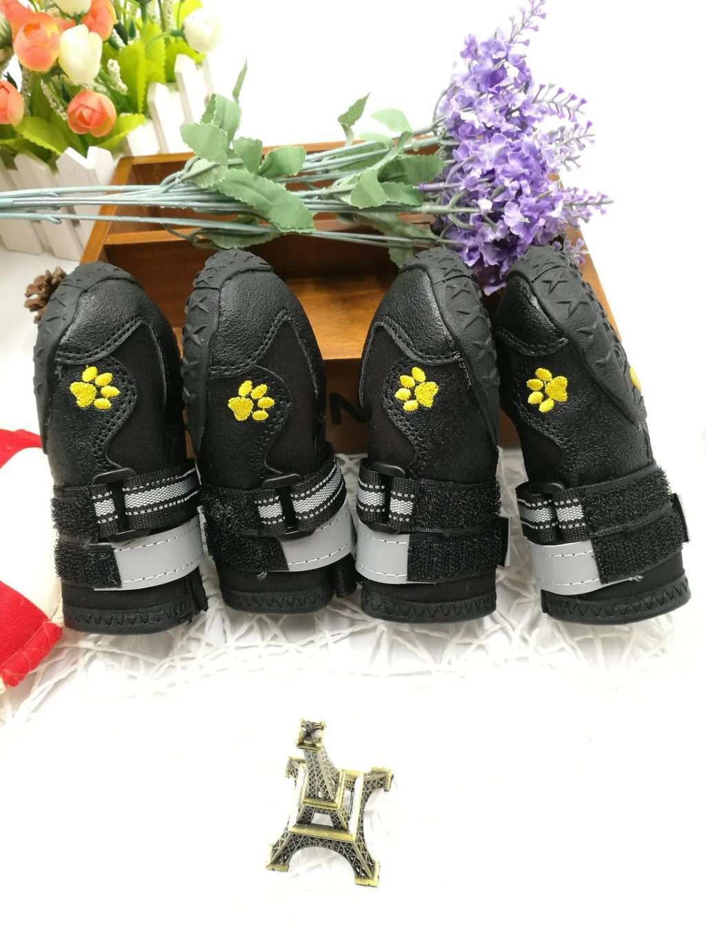 Black pet dog shoes with waterproof PVC sole and adjustable fuzzy belt on a light background