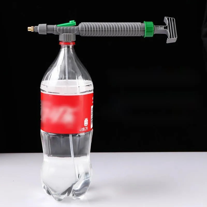 Plastic watering sprayer nozzle with extension tube attached to a large clear beverage bottle.