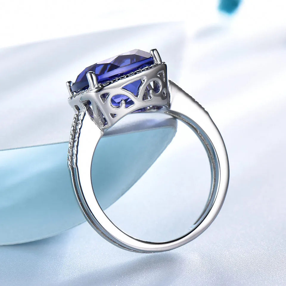 A blue tanzanite stone set in a sterling silver women's ring on a white background.