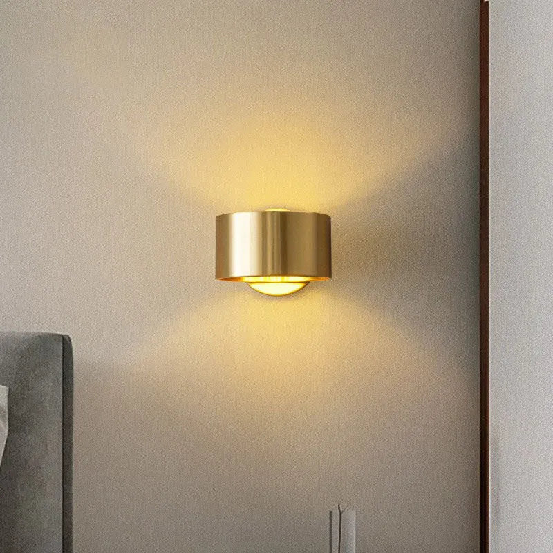 A simple modern copper wall lamp on a wall, shown in a black finish.