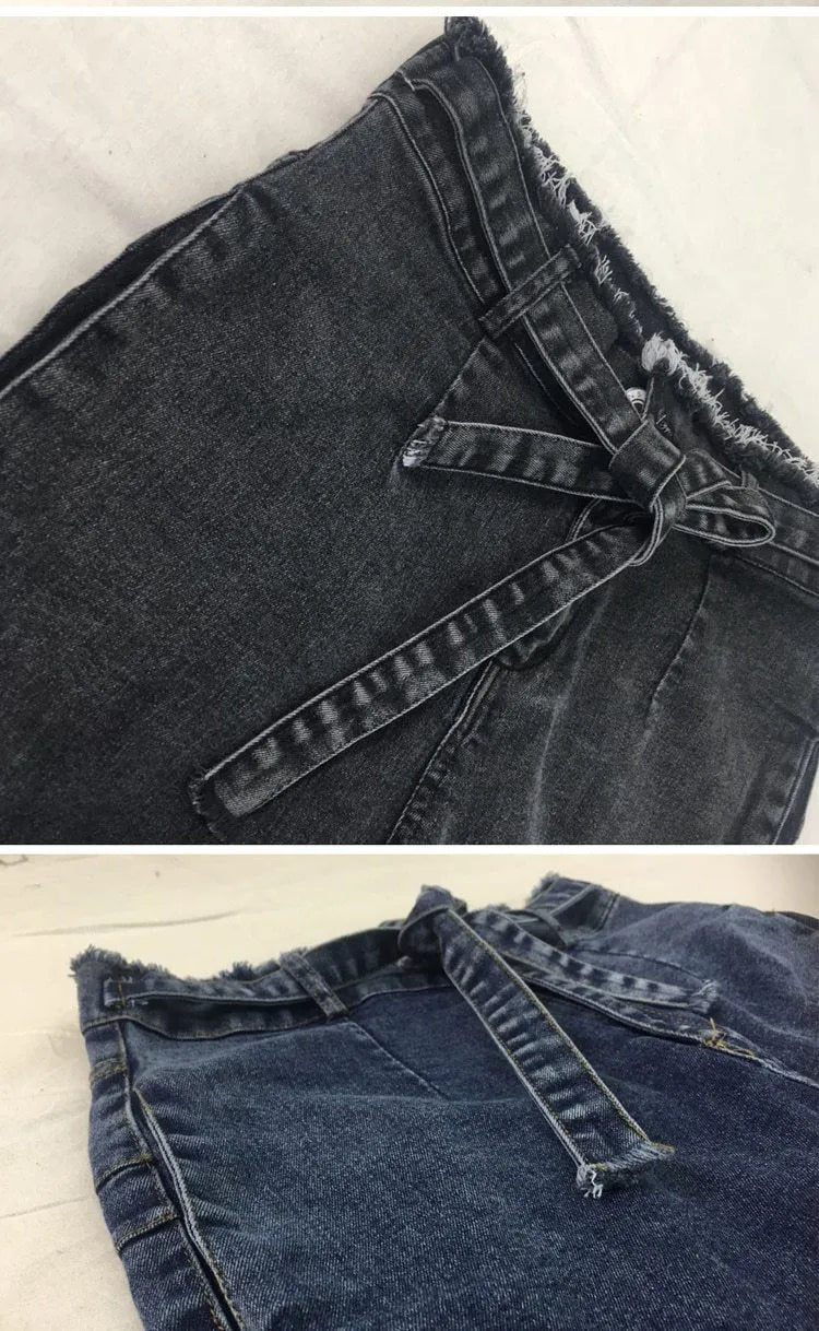 Pair of blue fringed jeans with a distressed hem laid flat, showing cowboy fabric texture.