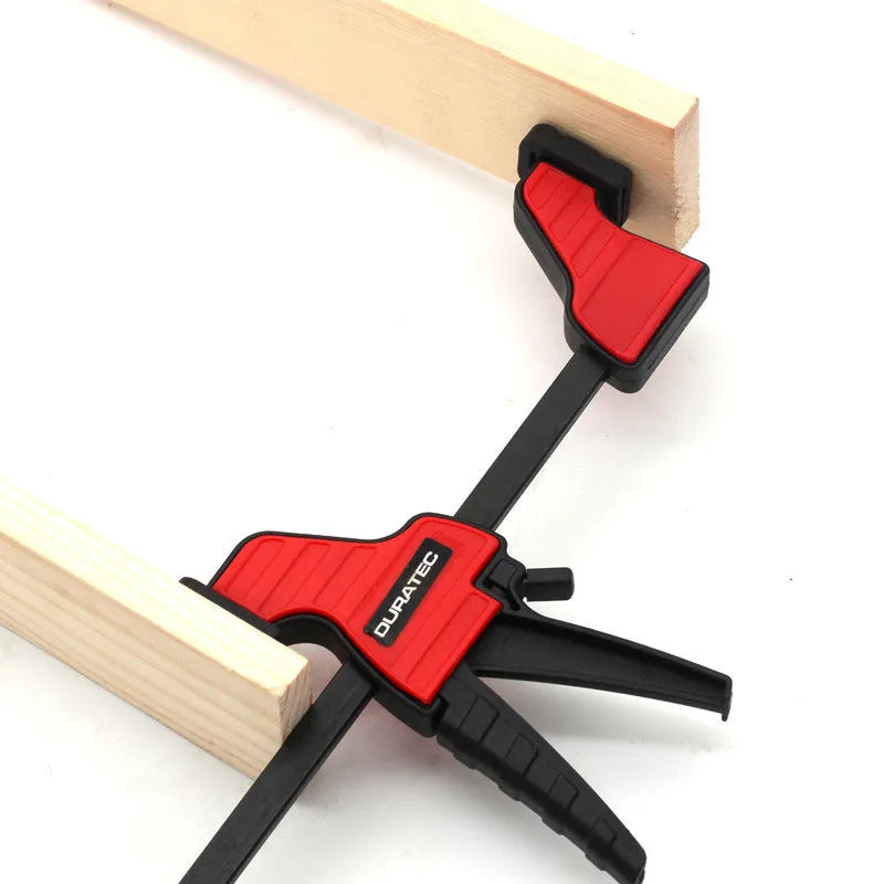 Black plastic woodworking clamp with quick-release trigger and soft rubber protective jaws.