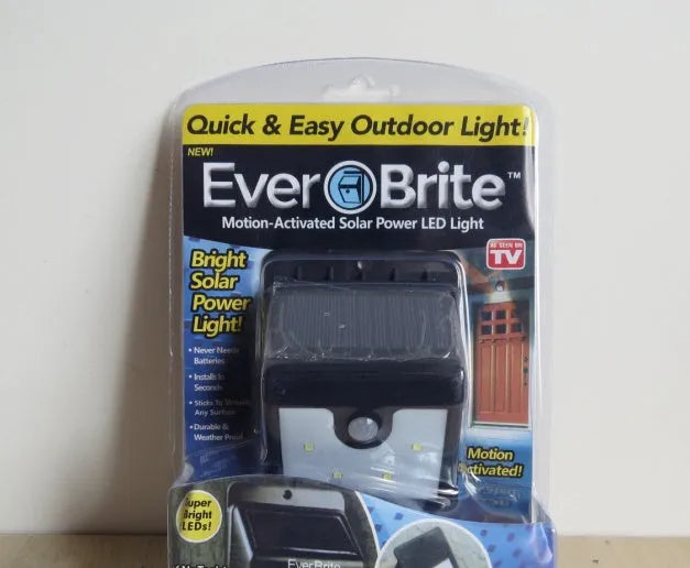 Set of four white outdoor solar security lights with motion sensor and adjustable mount on a garden fence