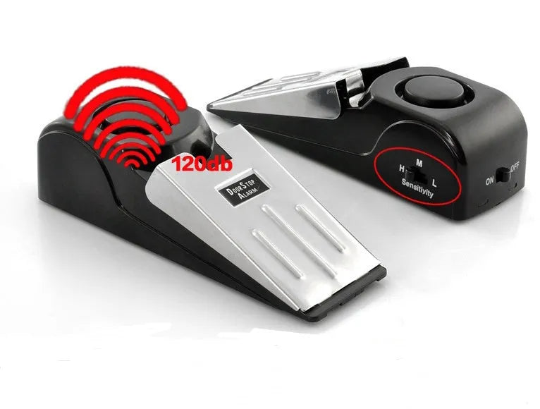 Black portable door stop alarm with wedge shape and stainless steel cover on a wooden floor.