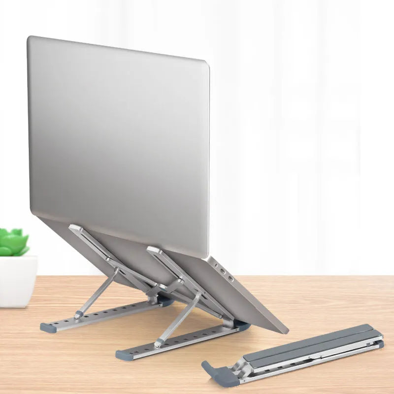 Folding aluminium laptop stand in silver, open and holding a laptop, with non-slip silicone pads visible