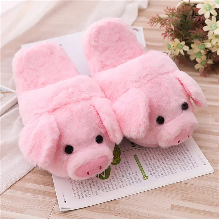 Pink pig-shaped plush house slippers with a short pile exterior, shown on a plain background.
