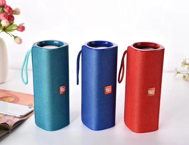 Cloth wireless Bluetooth speaker in multiple colours showing front grill and control buttons.