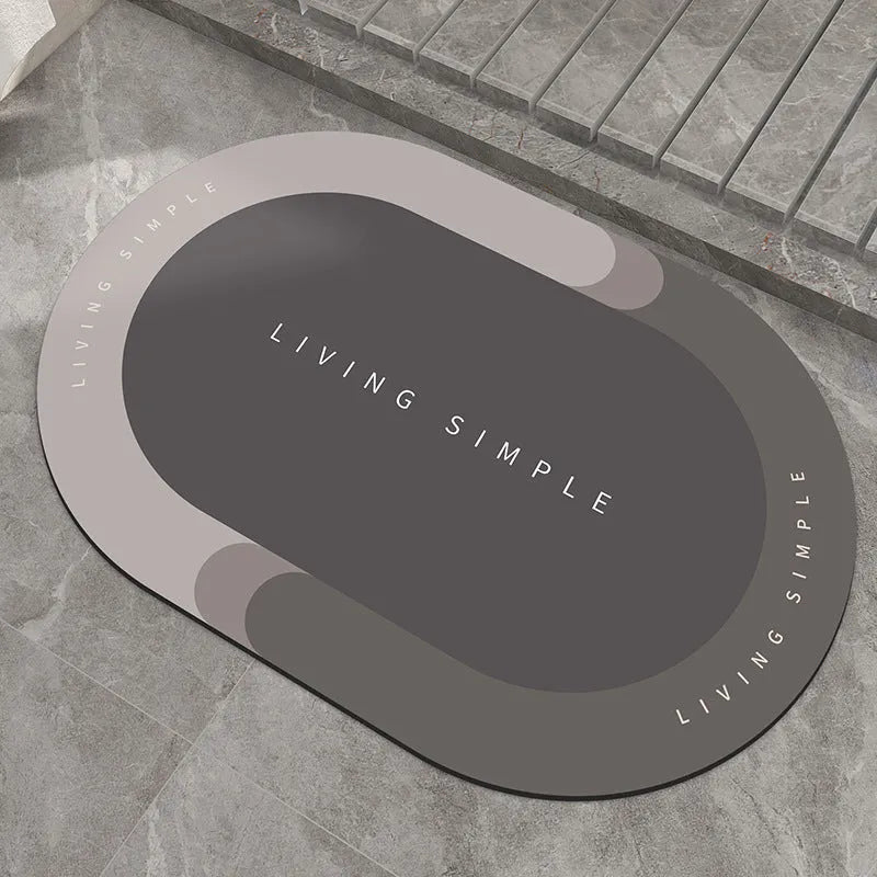 Oval grey polyester door mat with textured rubber non-slip backing on a wooden floor.