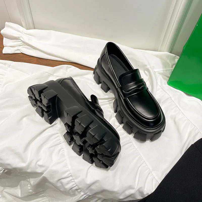A pair of wide fit patent leather loafers with a flat rubber sole on a neutral background.
