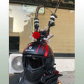 Gold-plated crown ornament with long black feather on motorcycle helmet, showing clip-on leather strap.