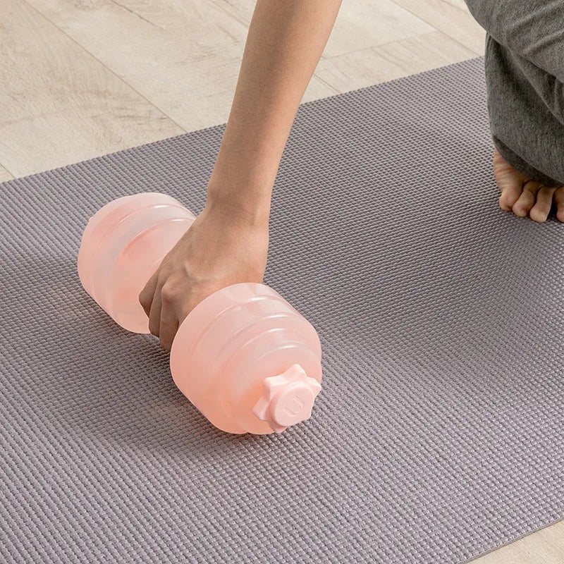 Mini portable plastic water dumbbell in transparent grey on flat surface with water filling opening visible