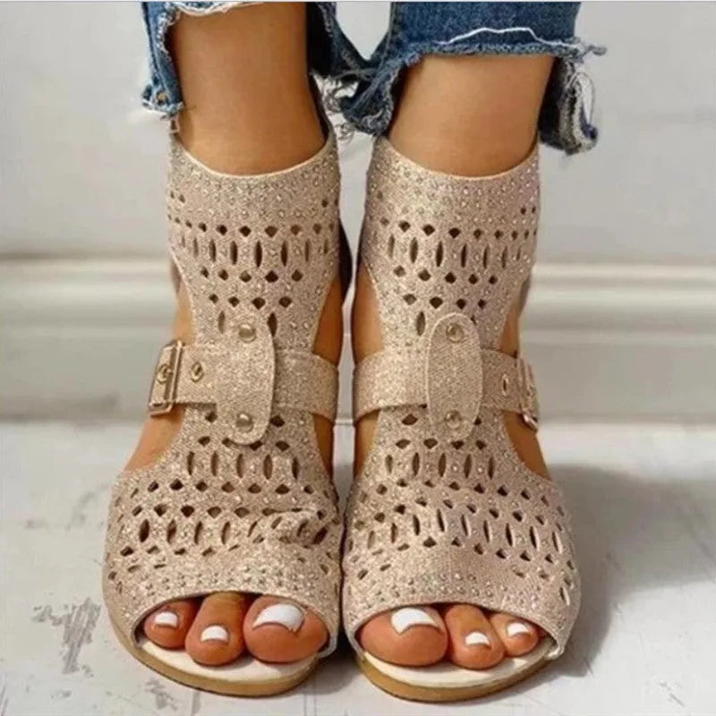 Women's beige rivet flat sandals with back zipper and low wedge heel on a white background.