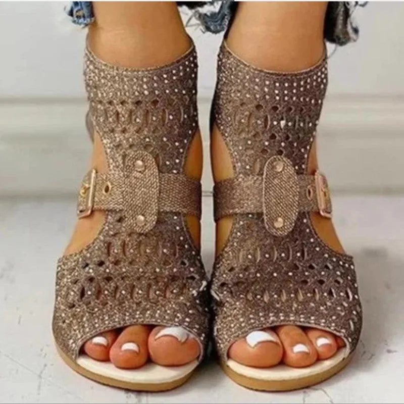 Women's beige rivet flat sandals with back zipper and low wedge heel on a white background.