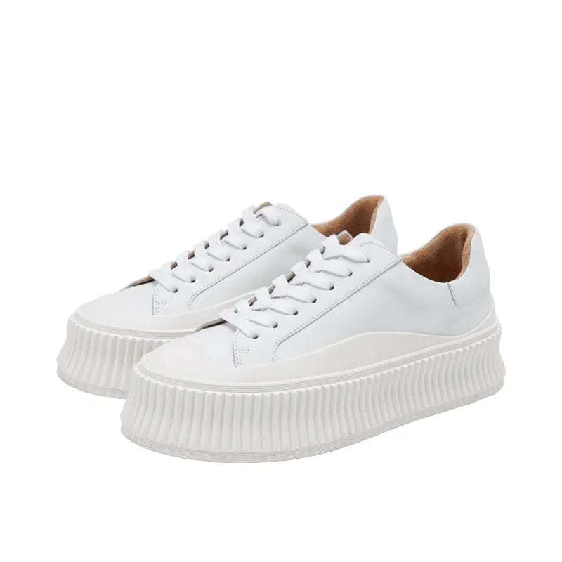 Women's white suede mid-top trainers with thick sole, back lacing, and cross binding detail on the heel.