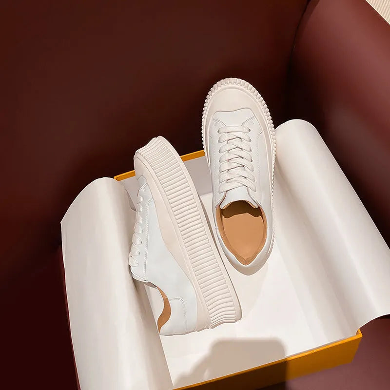 Women's white suede mid-top trainers with thick sole, back lacing, and cross binding detail on the heel.