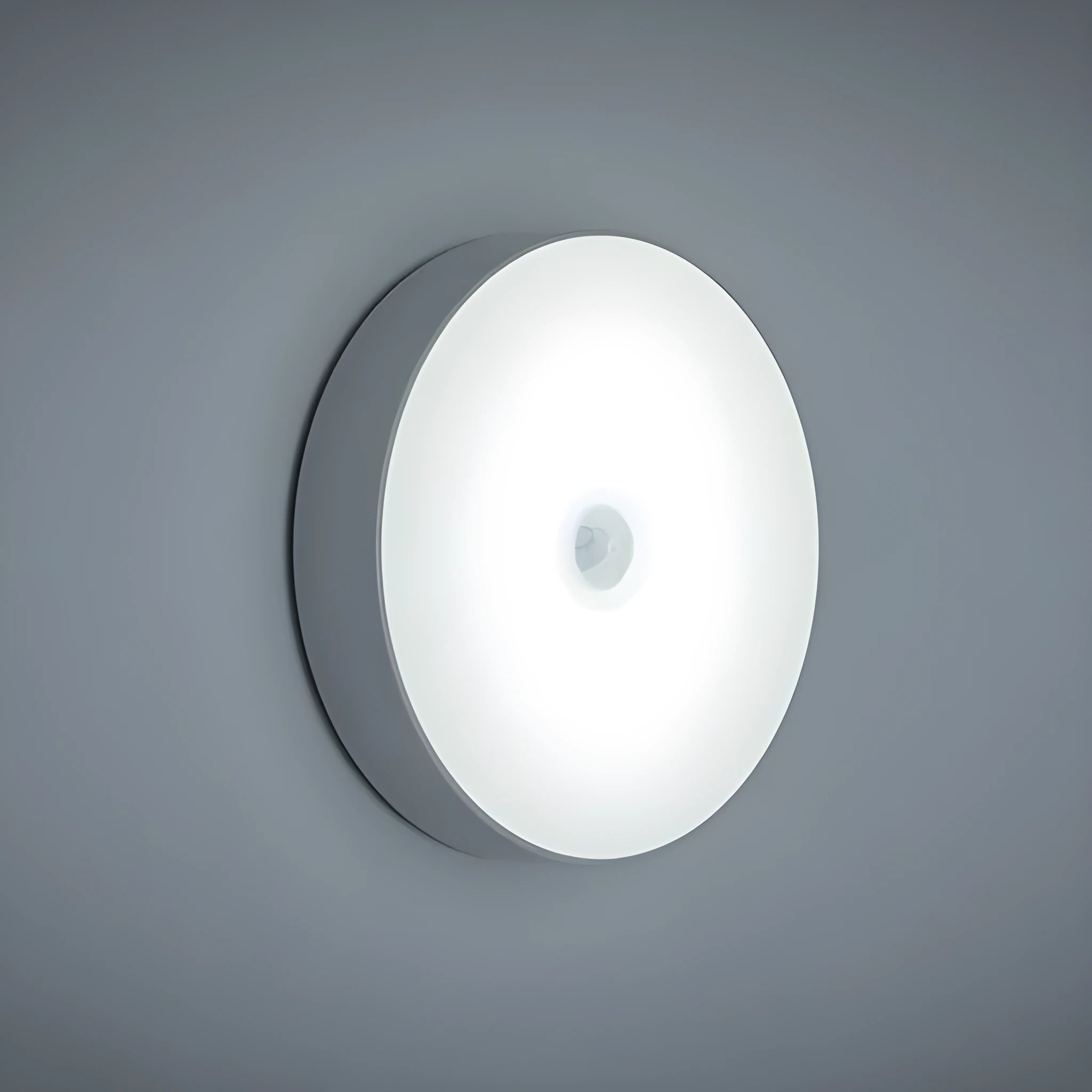 Small white circular LED body sensing night light with USB charging cable and adhesive tape.