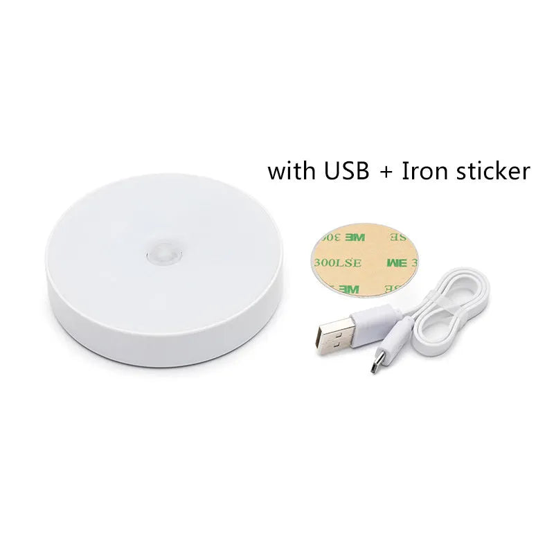 Small white circular LED body sensing night light with USB charging cable and adhesive tape.