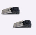 Black portable door stop alarm with wedge shape and stainless steel cover on a wooden floor.