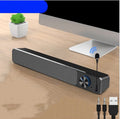 Black and white USB-powered desktop computer speakers with 2.0 stereo sound on a wooden desk.