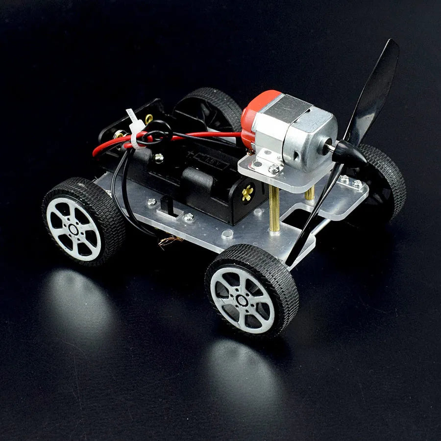 Assembled DIY wind car science experiment kit with acrylic, metal, and plastic parts on a table.