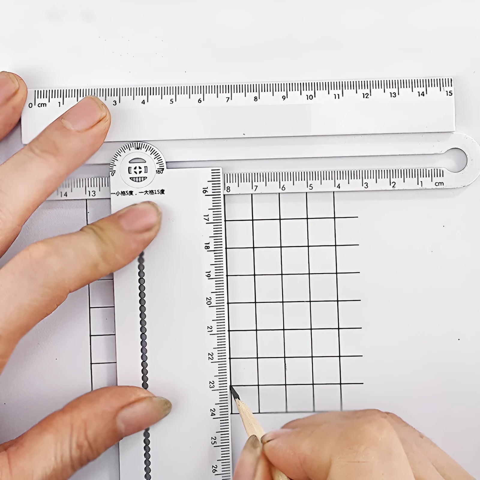 White plastic multi-function ruler measuring 30cm in length on a drawing surface.