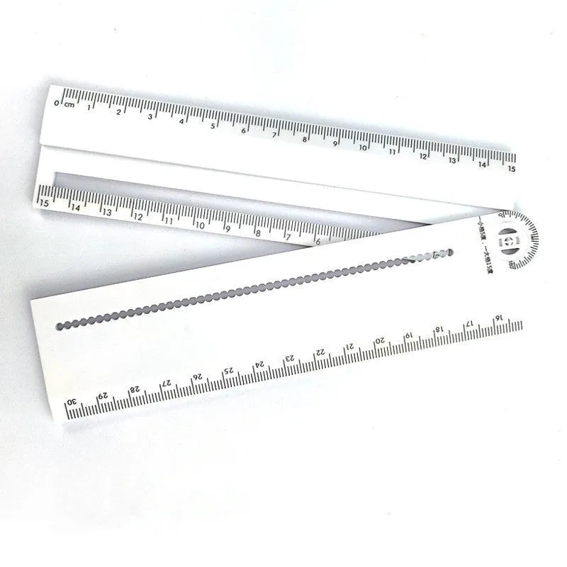 White plastic multi-function ruler measuring 30cm in length on a drawing surface.