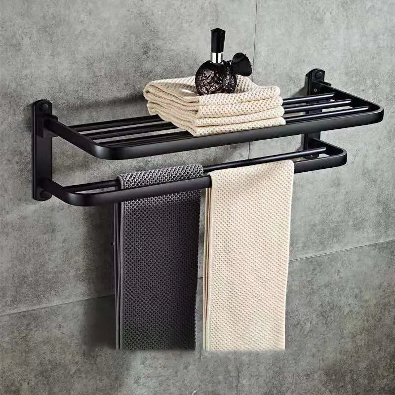 Silver aluminium two-tier folding towel rack with perforated shelves mounted on a bathroom wall.