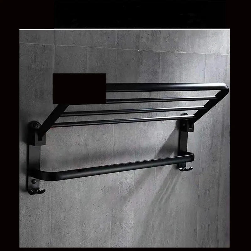 Silver aluminium two-tier folding towel rack with perforated shelves mounted on a bathroom wall.