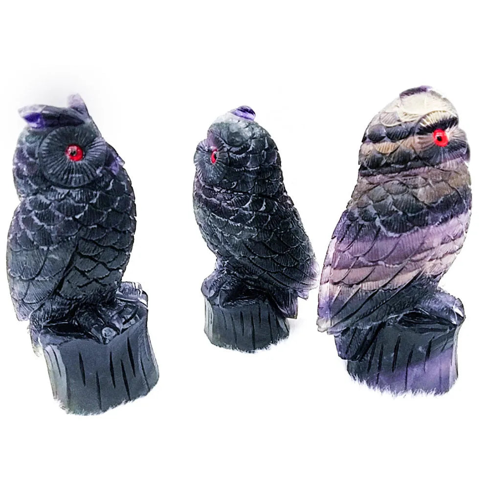 Hand-carved purple fluorite owl ornament on display surface showing natural colour variations