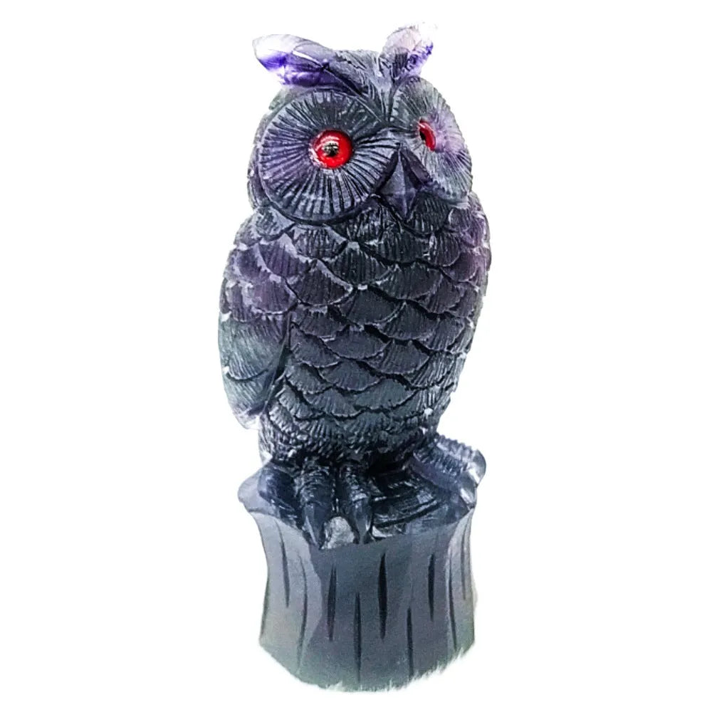 Hand-carved purple fluorite owl ornament on display surface showing natural colour variations