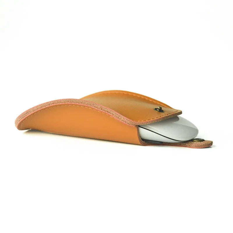 Brown leather storage bag for Apple Magic Mouse 2nd Generation, with a Magic Mouse partially visible inside, on a wooden desk.