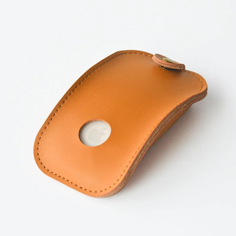 Brown leather storage bag for Apple Magic Mouse 2nd Generation, with a Magic Mouse partially visible inside, on a wooden desk.