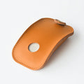 Brown leather storage bag for Apple Magic Mouse 2nd Generation, with a Magic Mouse partially visible inside, on a wooden desk.