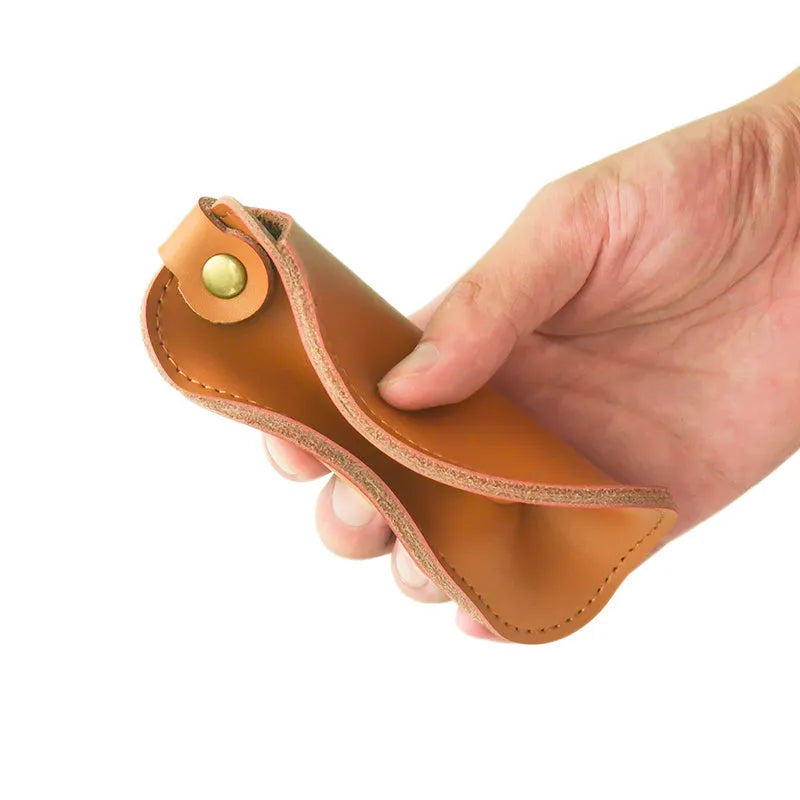Brown leather storage bag for Apple Magic Mouse 2nd Generation, with a Magic Mouse partially visible inside, on a wooden desk.