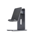 Dark space grey aluminium mobile phone holder with adjustable clamp and 360-degree ball joint on a wooden desk.