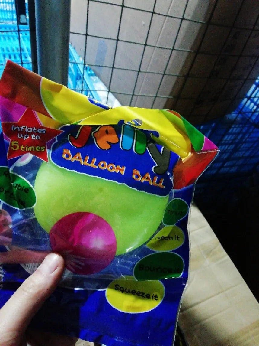 Assortment of inflated pink, yellow, blue and green TPR bouncy balls in different sizes on a plain background.