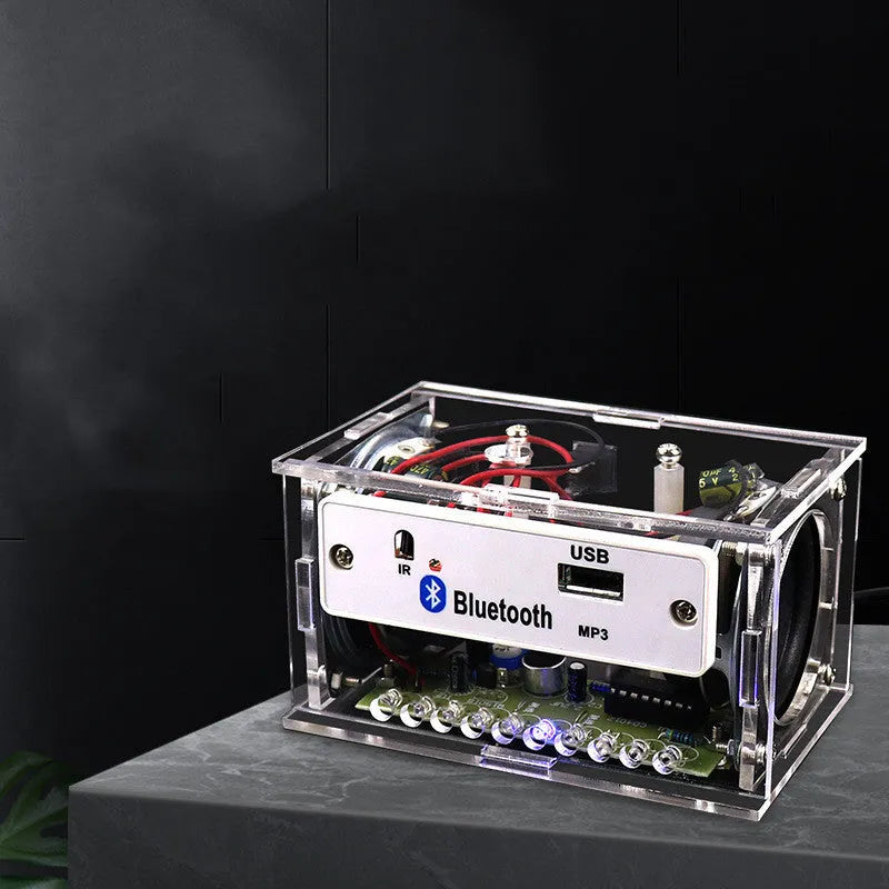 Bluetooth speaker DIY kit components including circuit board, loose electronics, speaker, and clear plastic shell.