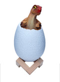Cool white 3D dinosaur egg night light with touch sensor and remote control on a wooden stand.