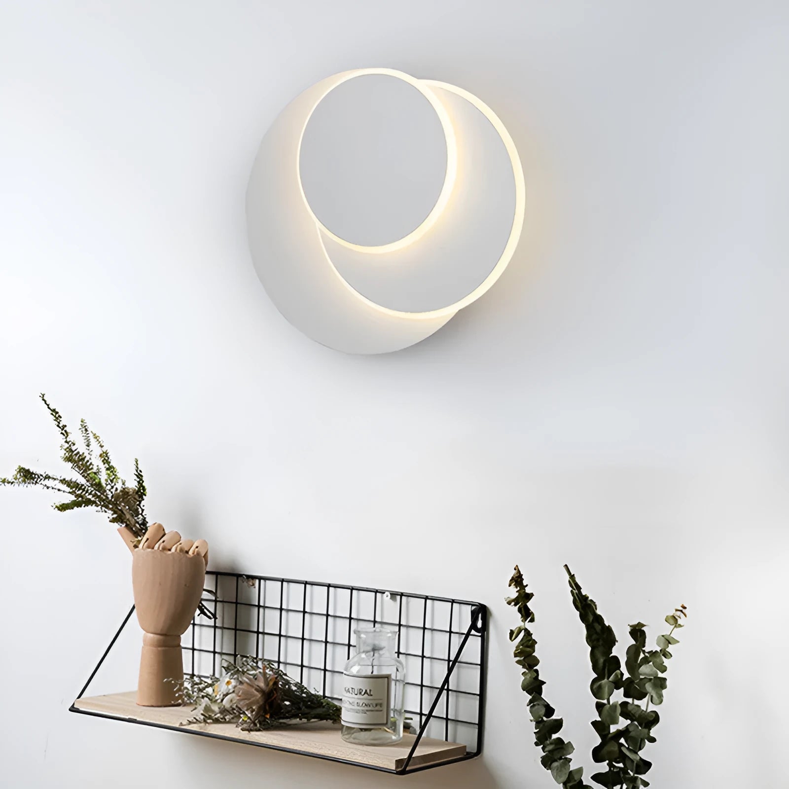 Modern round wall lamp with white acrylic shade and decorative circles on a wall.