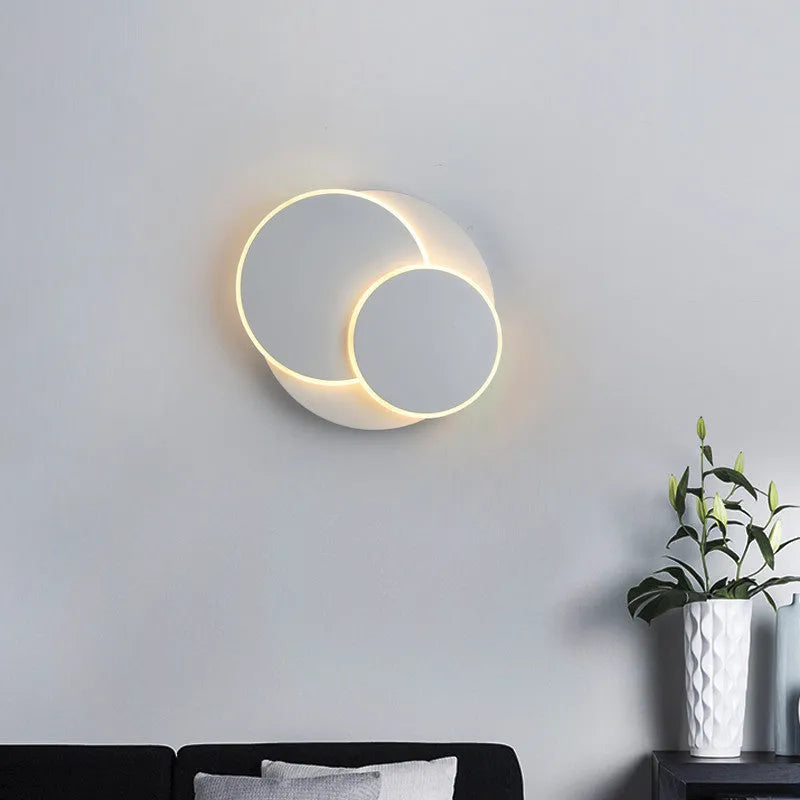Modern round wall lamp with white acrylic shade and decorative circles on a wall.