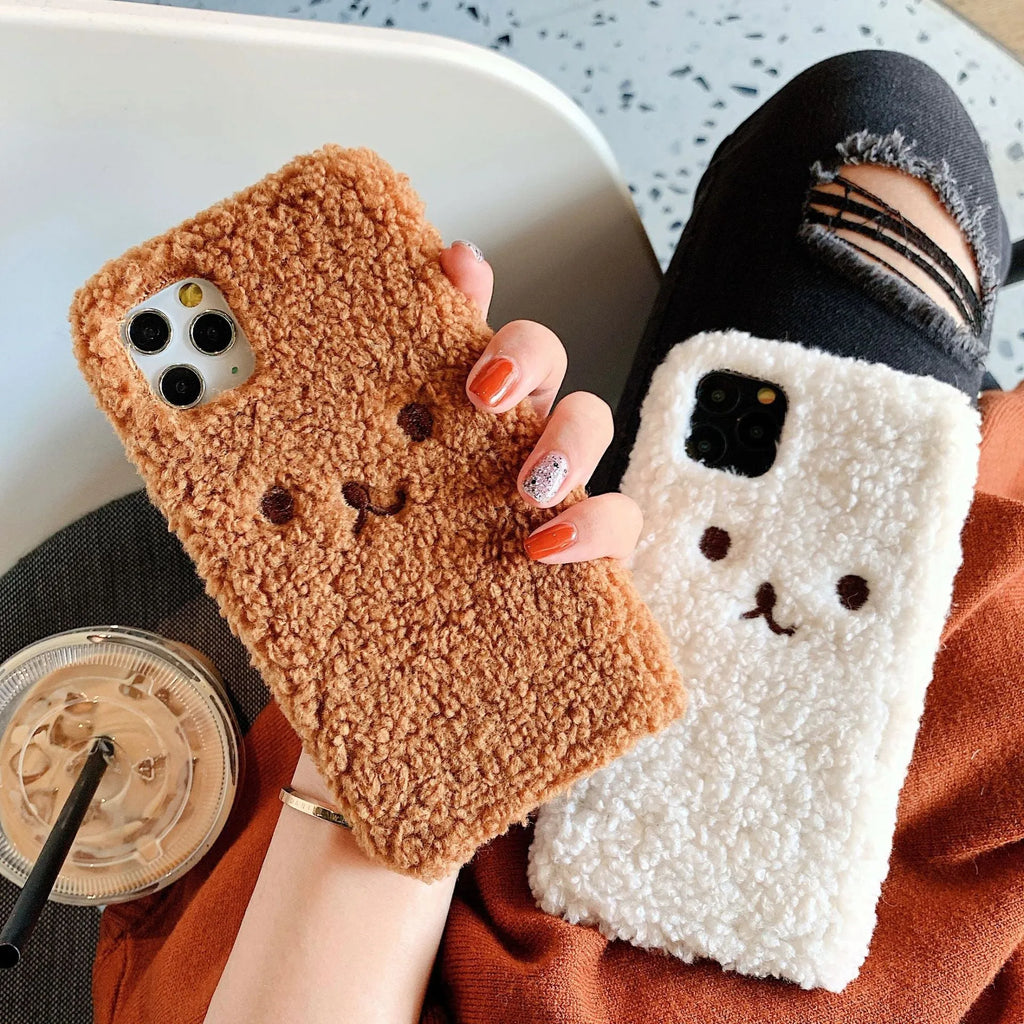 Brown embroidered plush bear face on a soft TPU phone case for iPhone, showing camera cut-out and raised edges.