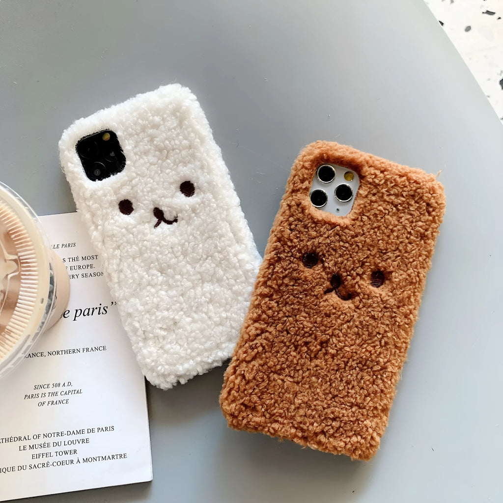 Brown embroidered plush bear face on a soft TPU phone case for iPhone, showing camera cut-out and raised edges.