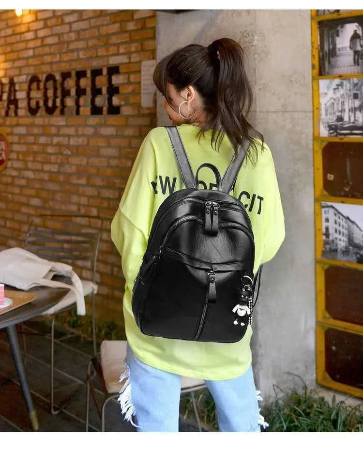 Medium black backpack with soft PU leather surface, showing double straps and zipper opening.