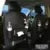 Black PU leather car seat back organiser with multiple pockets hanging from a car headrest