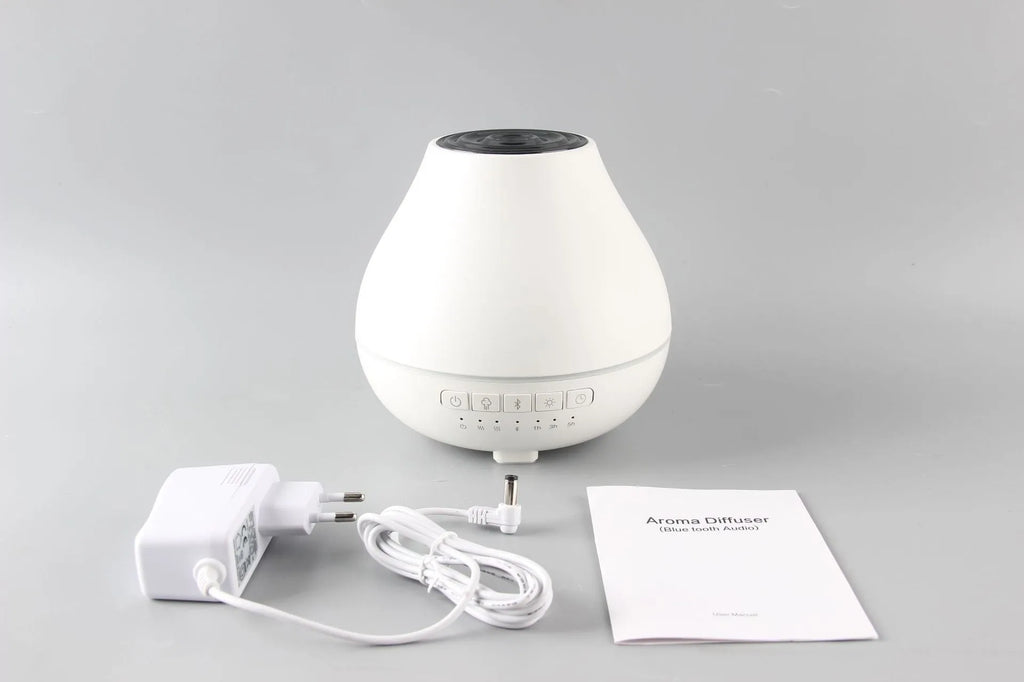 White round Bluetooth aroma diffuser and humidifier with night light on a wooden surface.
