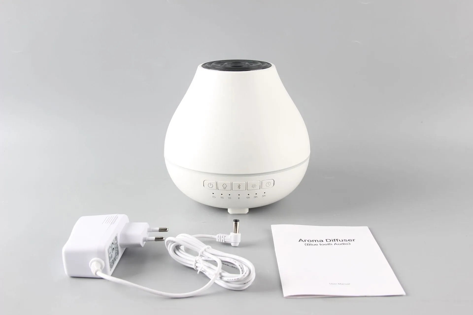 White round Bluetooth aroma diffuser and humidifier with night light on a wooden surface.
