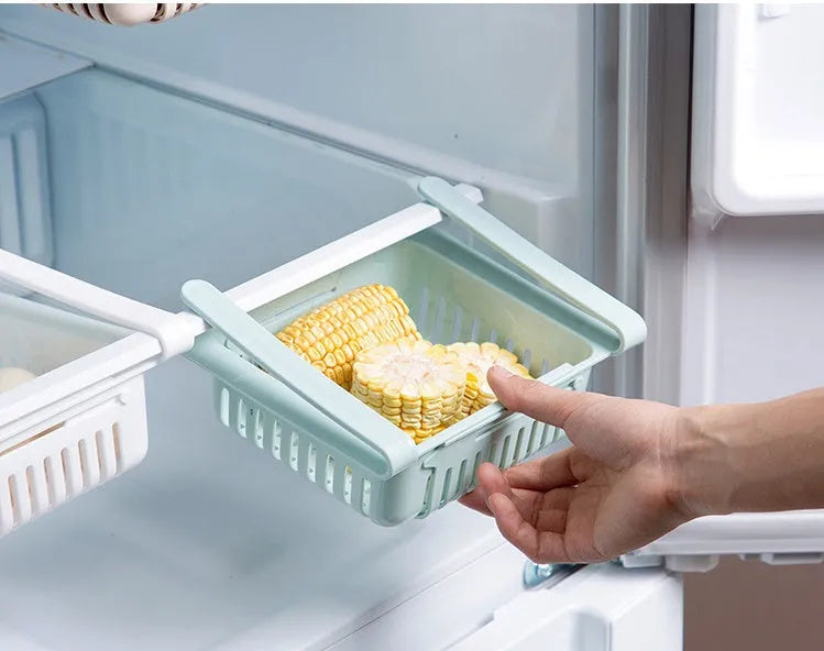 Blue telescopic plastic storage basket for refrigerator organisation with fruits and vegetables inside.