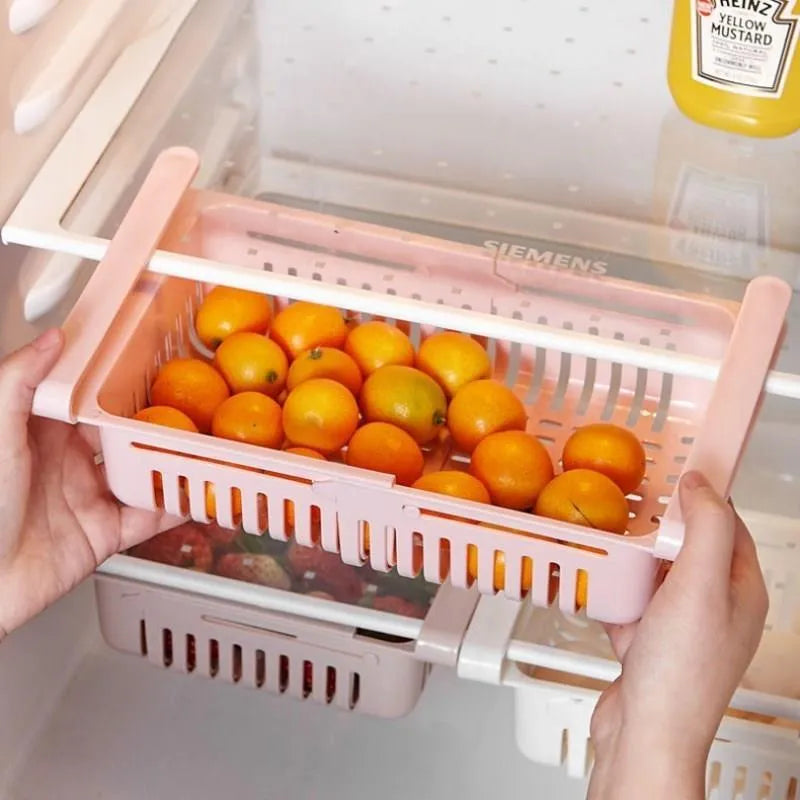 Blue telescopic plastic storage basket for refrigerator organisation with fruits and vegetables inside.