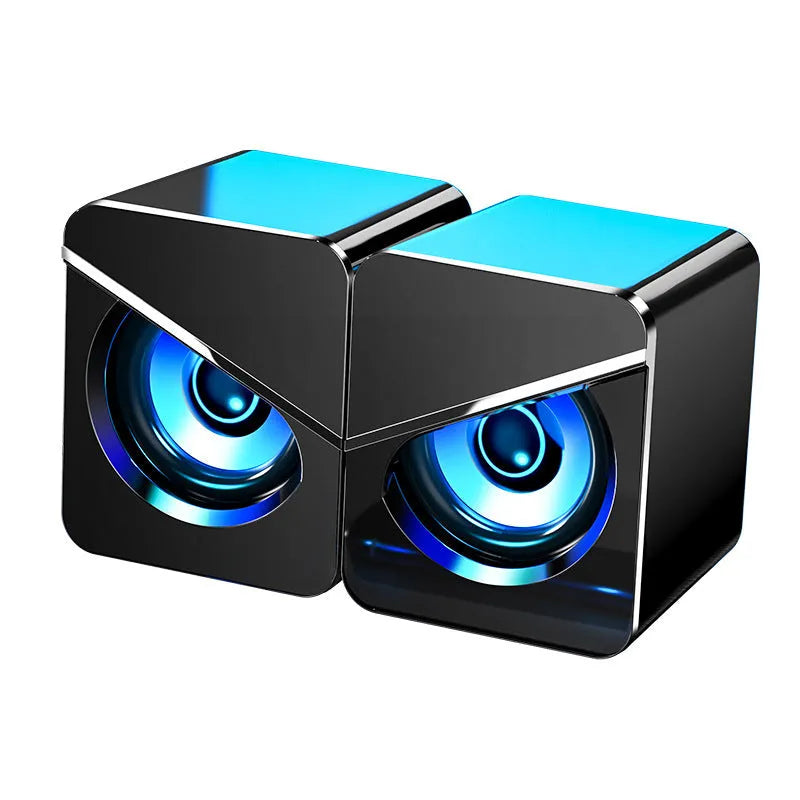 Small black and white plastic desktop computer speakers with 3.5mm cable and battery compartment